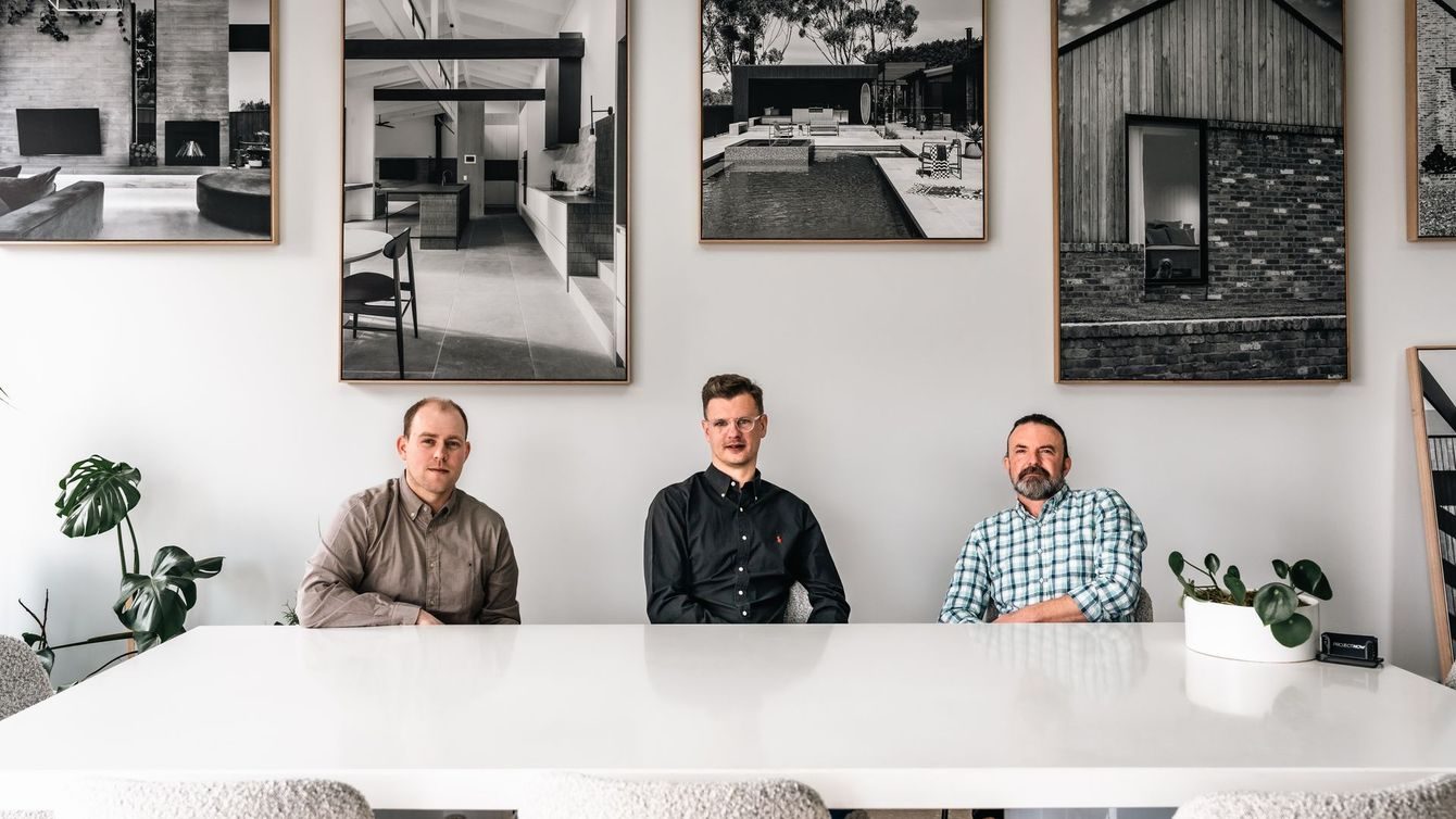 Louis Krause, Luke Jennings and Jason Hopgood of Project Now Architects seated at a white table beneath framed architectural photographs