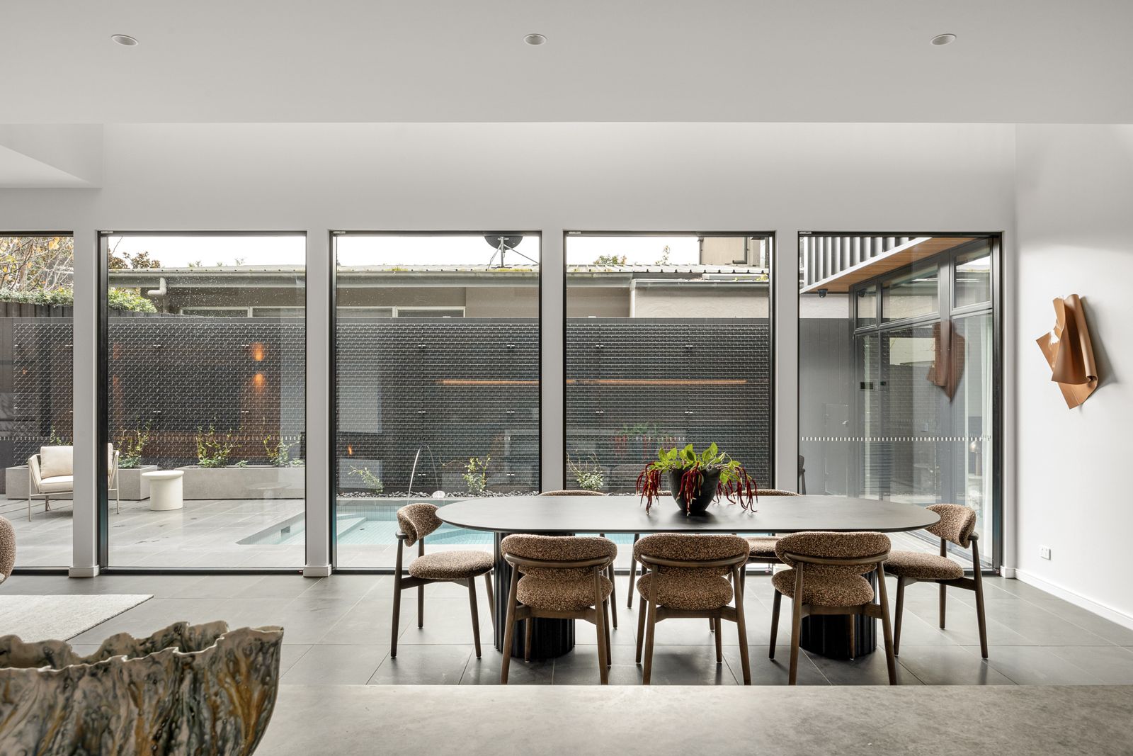 Dining area at The Ora looking through floor-to-ceiling windows to the pool and courtyard