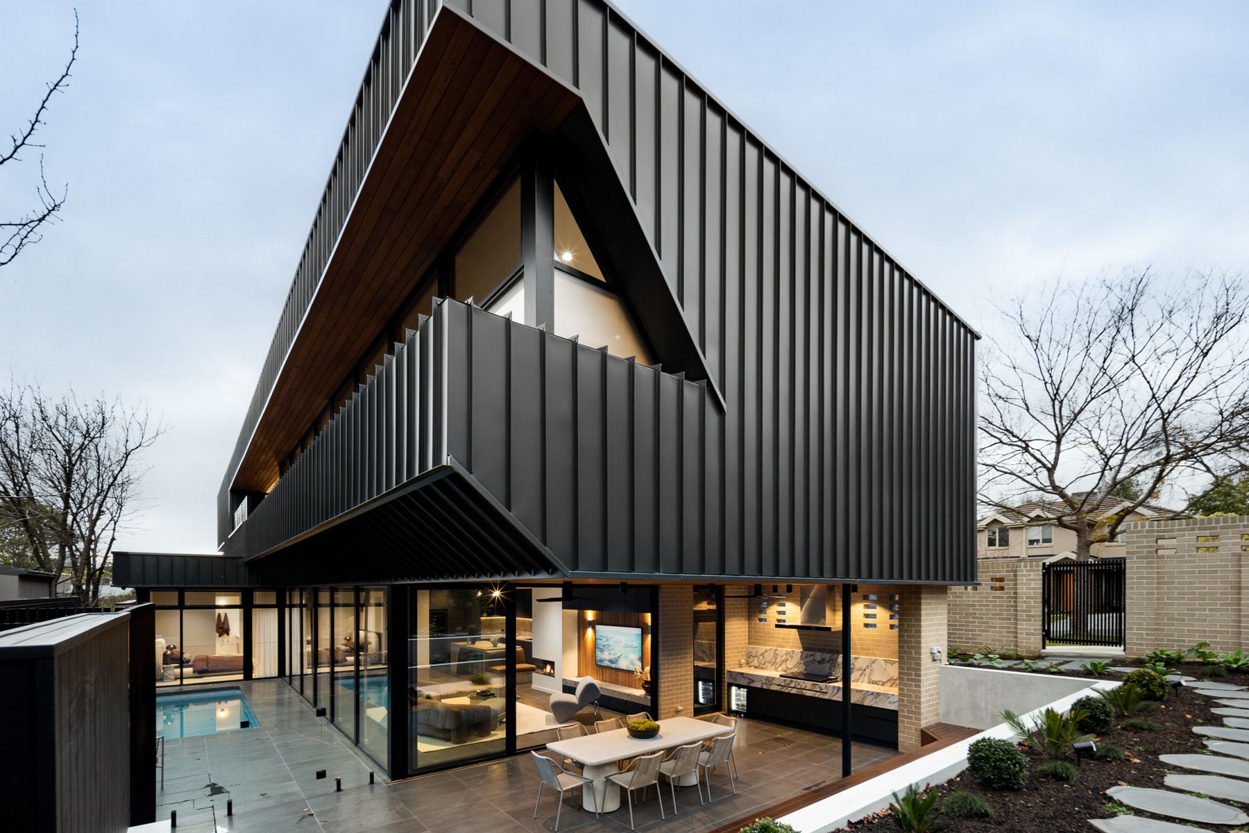 Rear of The Ora at dusk with the Plungie Max pool and illuminated living spaces