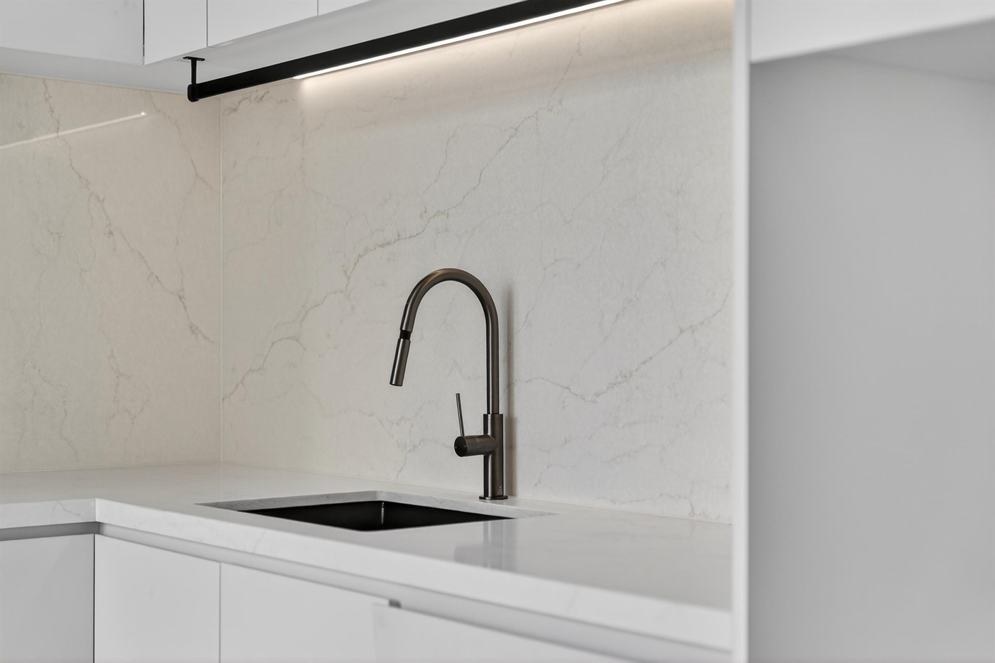 Kitchen with stone splashback and black tapware selected for a Varcon home in Essendon