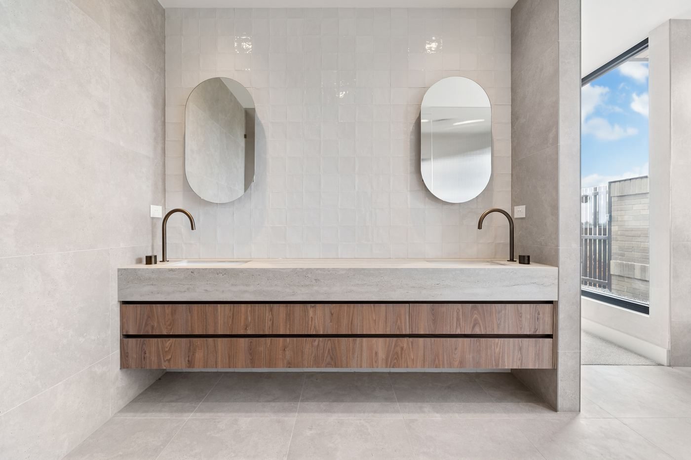 Bathroom vanity at Musk with oval mirrors and a floating timber-fronted unit