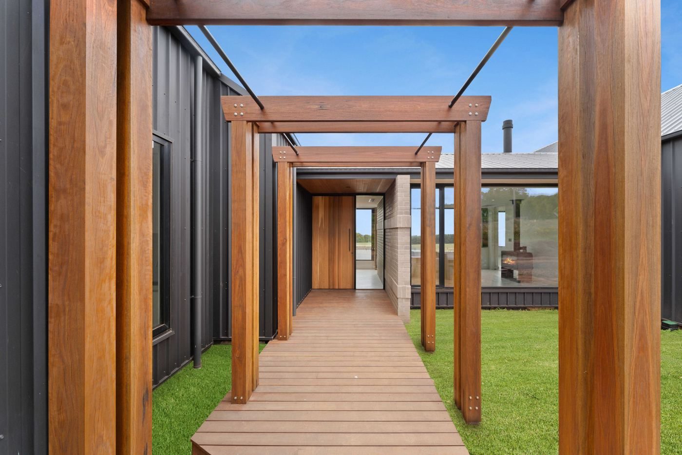 Timber pergola walkway at Musk between dark-clad volumes, showing material junctions and detailing