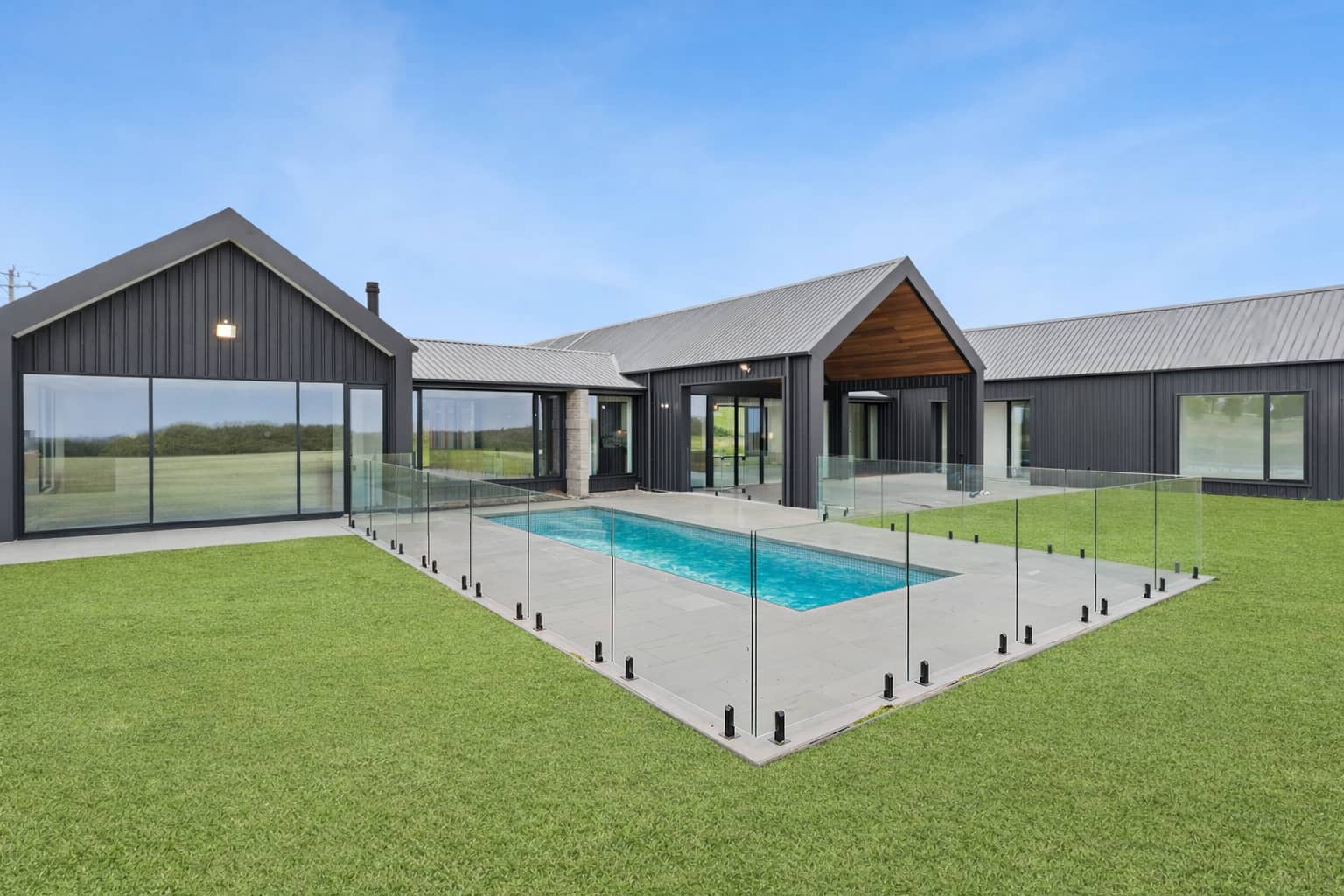 Pool terrace and lawn at Musk, surrounded by dark-clad gabled wings
