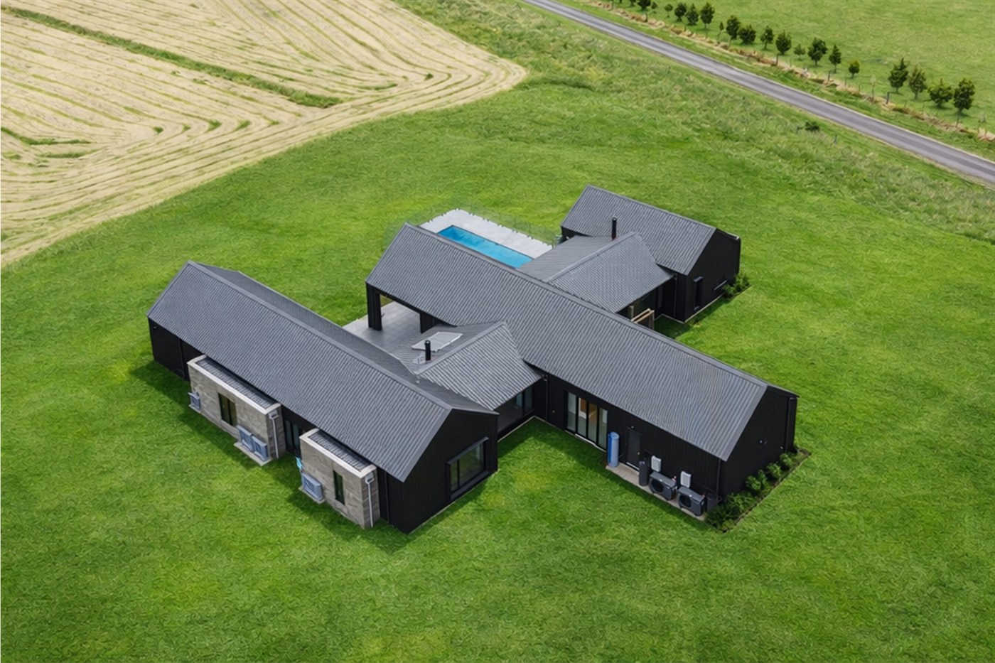 Aerial view of Musk, a single-storey rural home of connected gabled volumes set in open paddocks